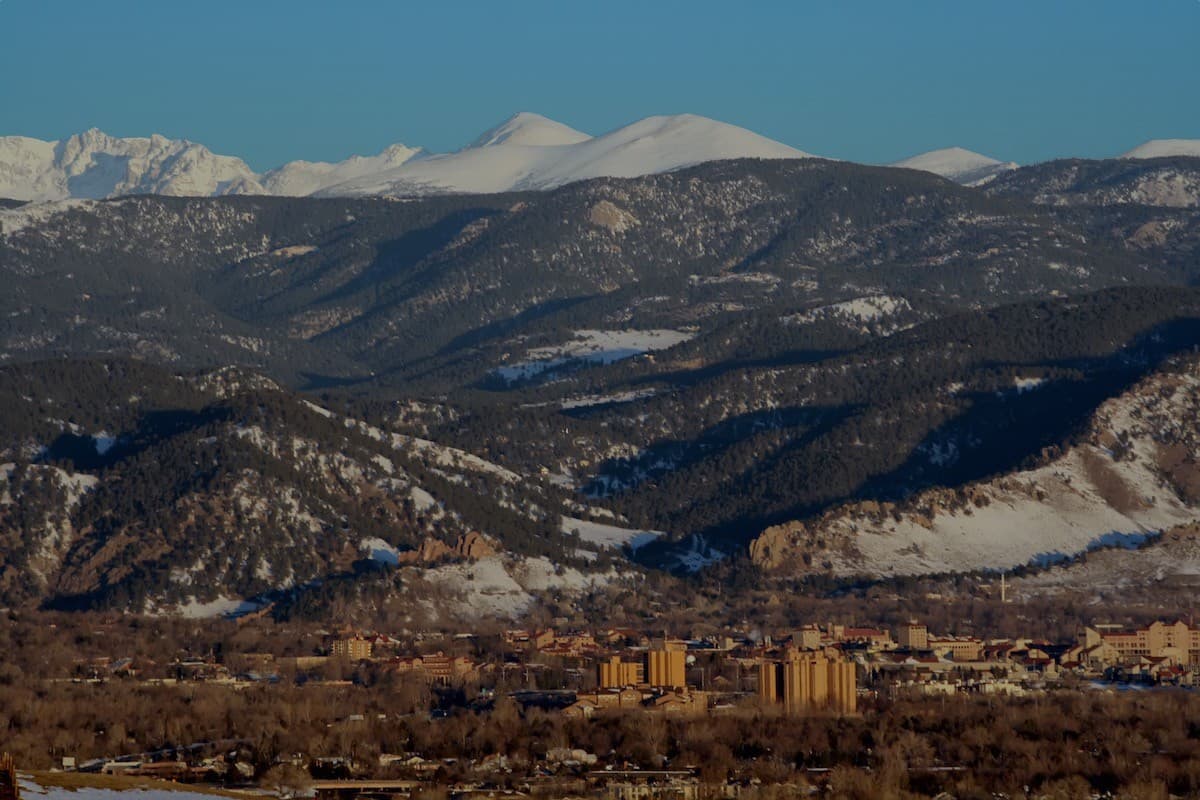 The Front Range mountains rising behind a town on the plains